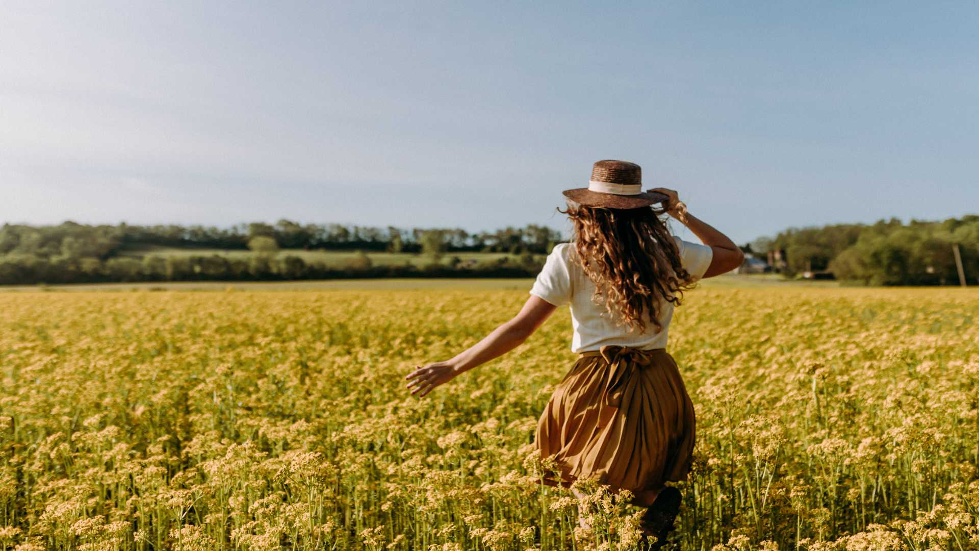 femme dans un champ de fleurs l'été pour fêter Lughnasadh