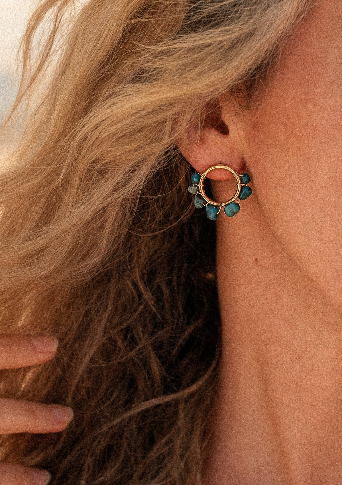 Boucles d'oreilles cercles Azurite Peau salée, anneau doré serti de pierres brutes bleues, portées en bord de mer cheveux au vent – Namaka collection Solaire