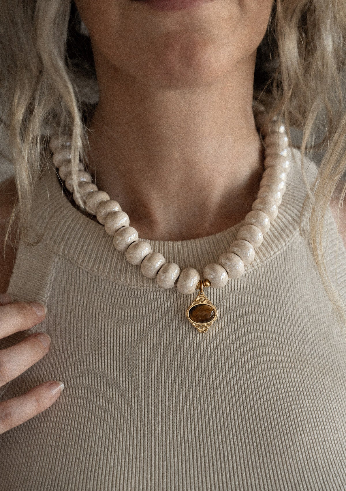 Collier ras-de-cou perles céramique crème pendentif Œil de Tigre porté sur débardeur côtelé beige, pierre de courage assemblé en France