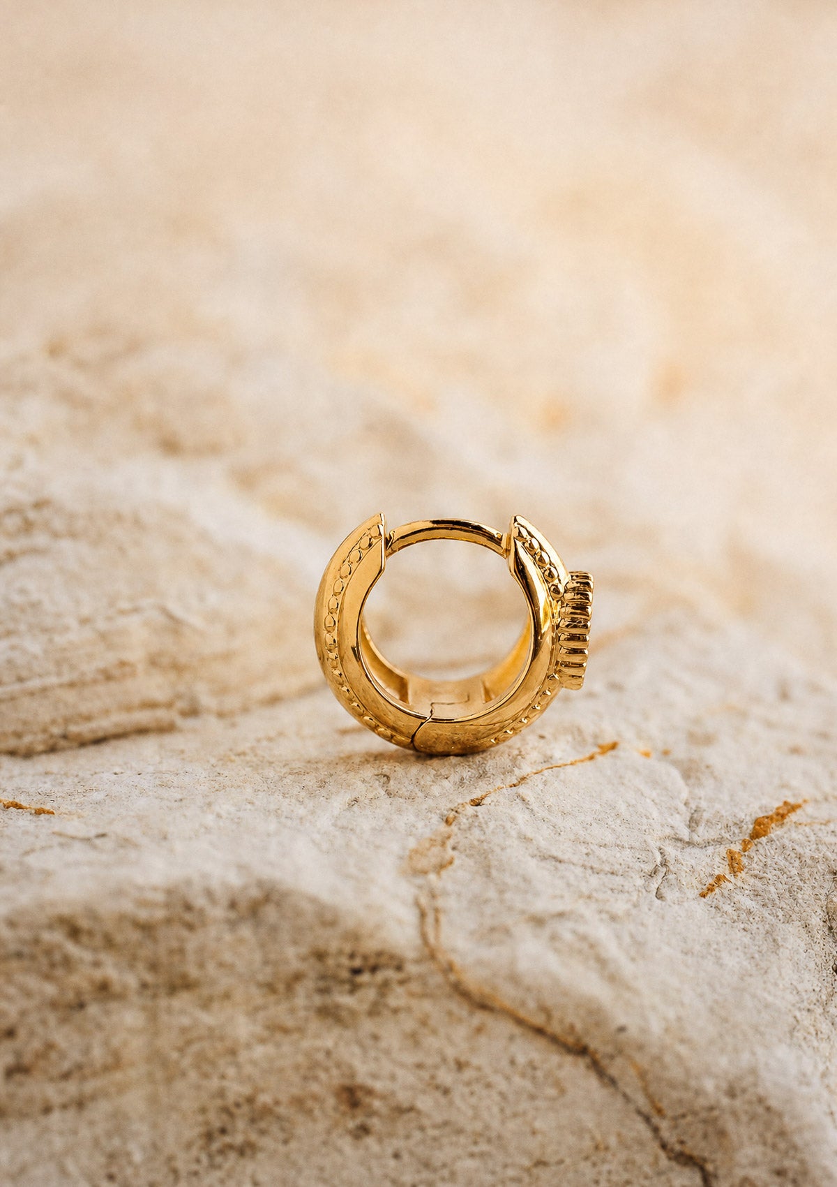 Vue de profil de la mini créole Quartz Fumé en or recyclé 18 carats, format huggie texturé et bombé signé Namaka