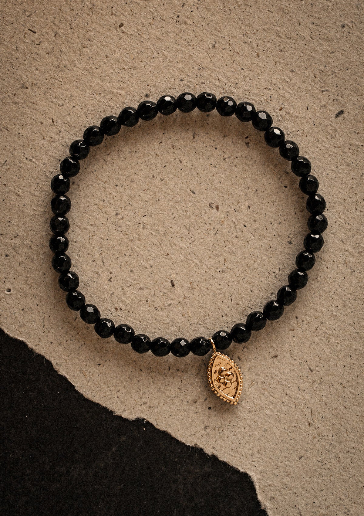 Packshot bracelet élastique or recyclé 18 carats perles Onyx Noir facettées 4 mm avec charm marquise doré gravé, pierre d'ancrage