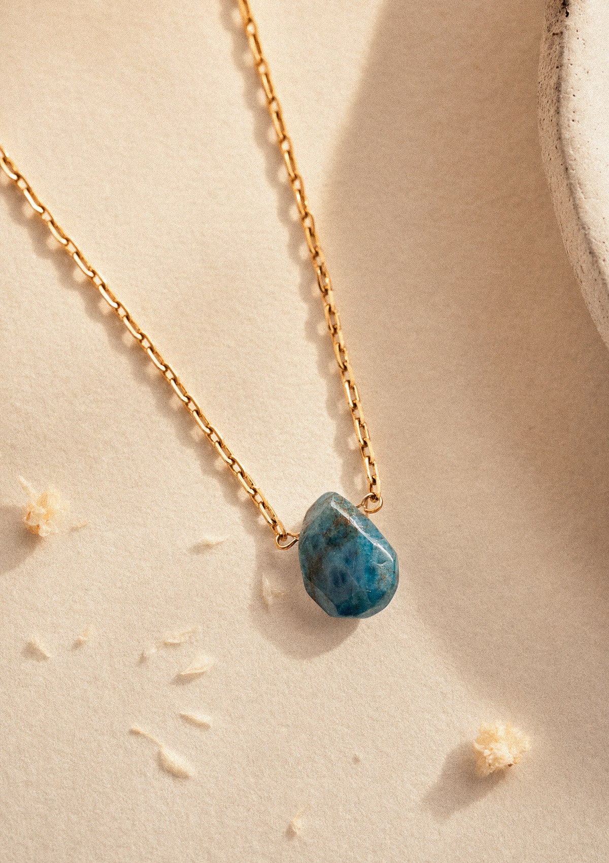 Collier Éclat Brut packshot, chaîne fine dorée et pierre d'Apatite bleu néon facettée en goutte, bijou intuition et clarté – Namaka collection Solaire, assemblé en France