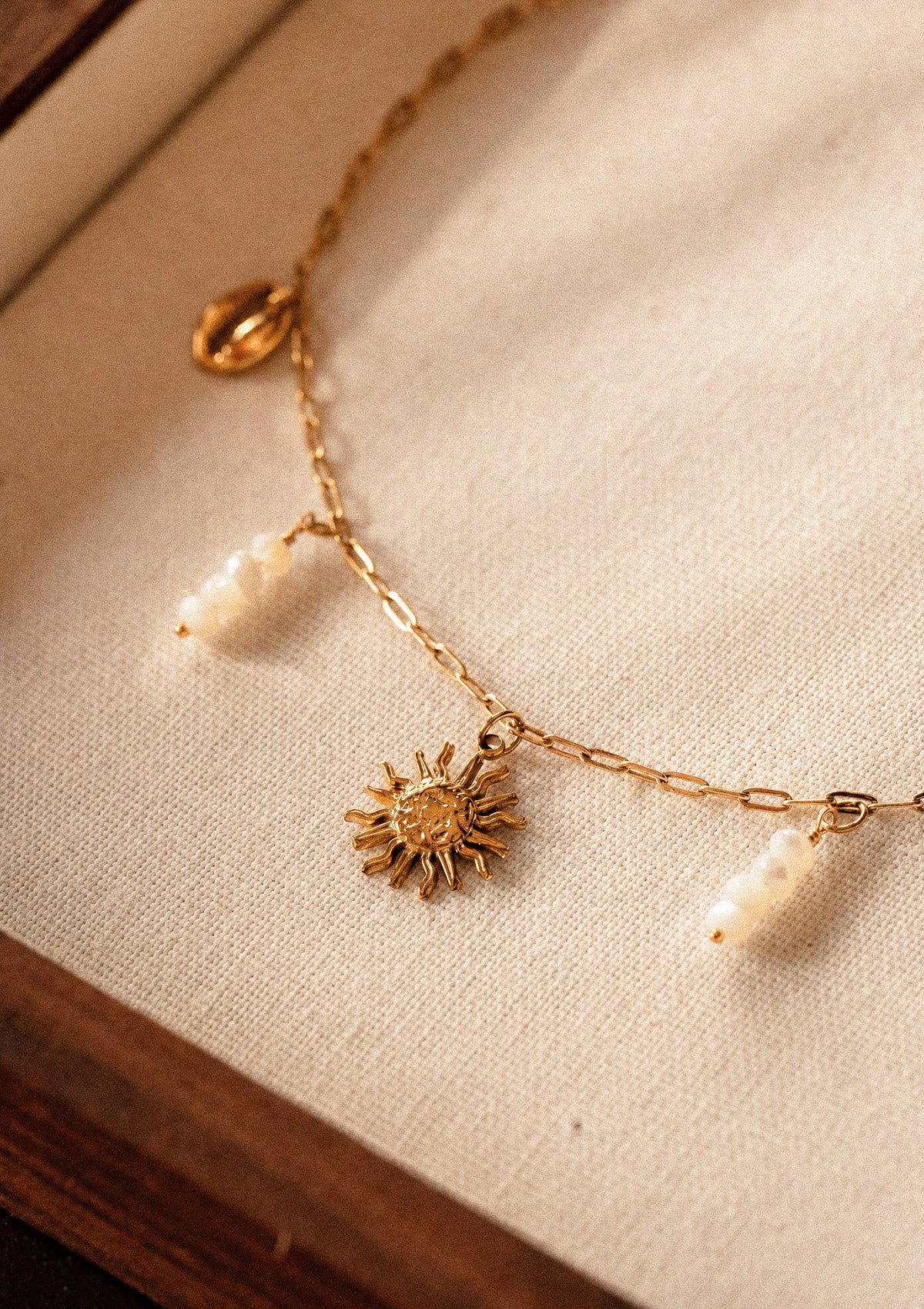 Gros plan du pendentif soleil rayonnant et perles de Nacre naturelles du collier Rivage d'Été, détail bijou solaire Namaka collection Solaire assemblé en France