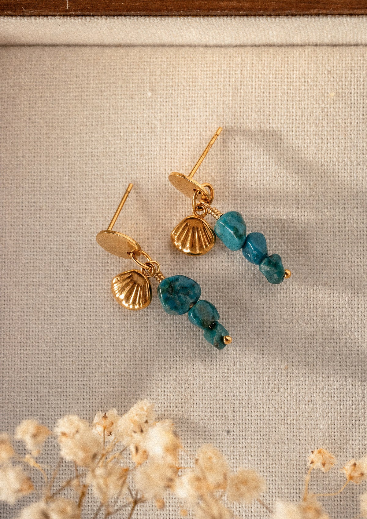 Boucles d'oreilles Azurite Coquillage Intuitif packshot posées sur toile, charms coquillage doré et perles d'Azurite bleu turquoise – Namaka collection Solaire, assemblé en France
