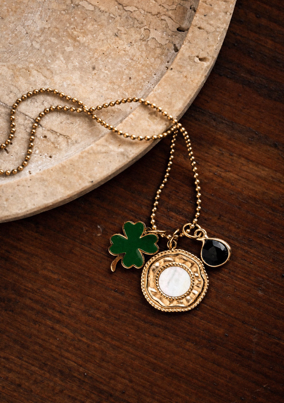 Packshot collier chaîne à billes acier doré trois charms : trèfle vert émaillé, Nacre blanche, goutte Onyx Noir, assemblé en France