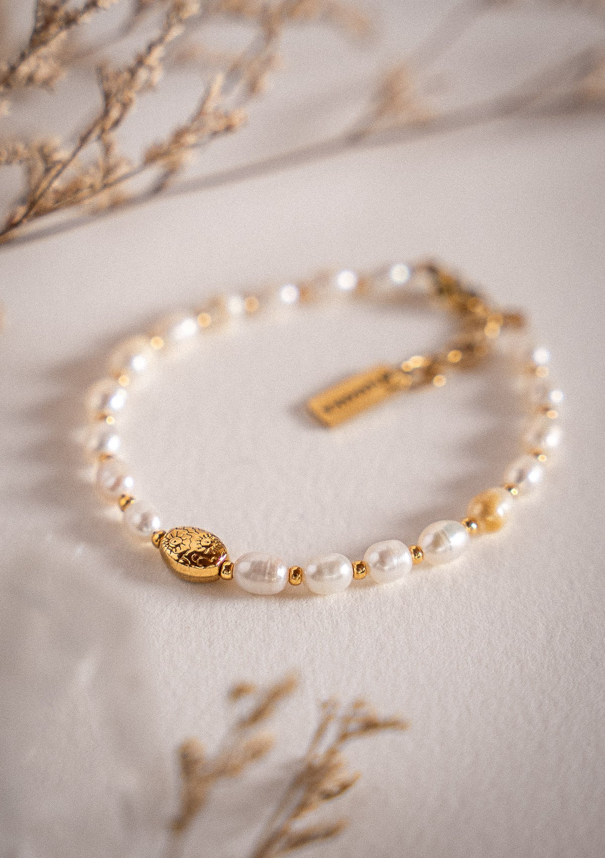 Bracelet en acier inoxydable doré
Pierres : Perles d’eau douce ovales naturelles
Ornement central : perle ovale gravée fleurie
Assemblé en France