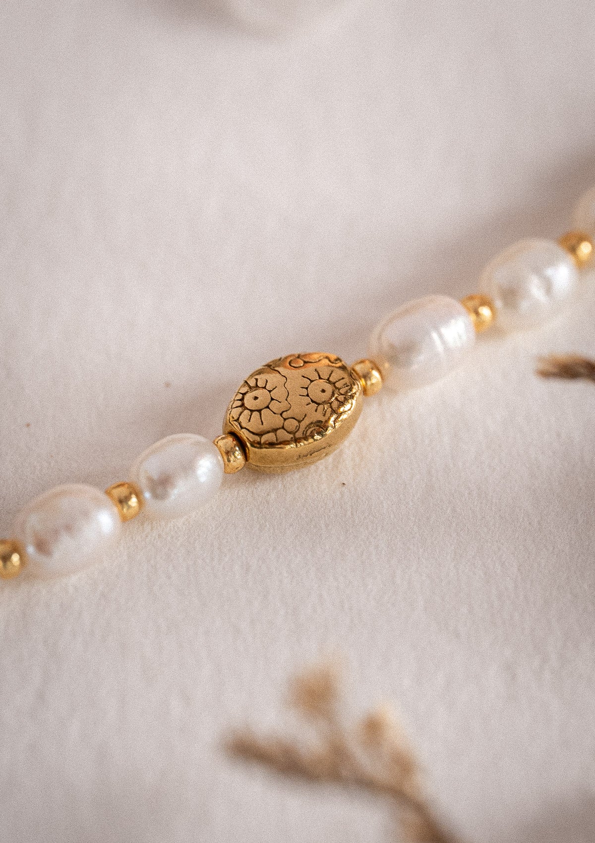 Bracelet en acier inoxydable doré
Pierres : Perles d’eau douce ovales naturelles
Ornement central : perle ovale gravée fleurie
Assemblé en France