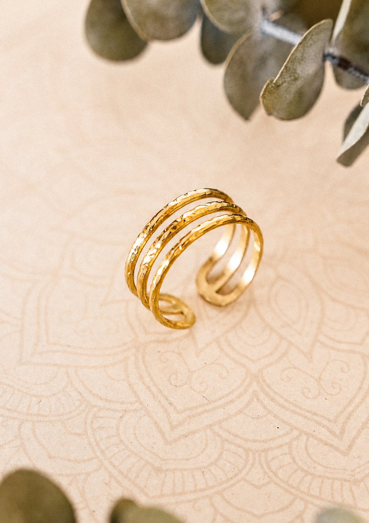 Détail de la bague Sillage Doré en acier inoxydable doré brillant, triple anneau aux reliefs martelés solaires signé Namaka