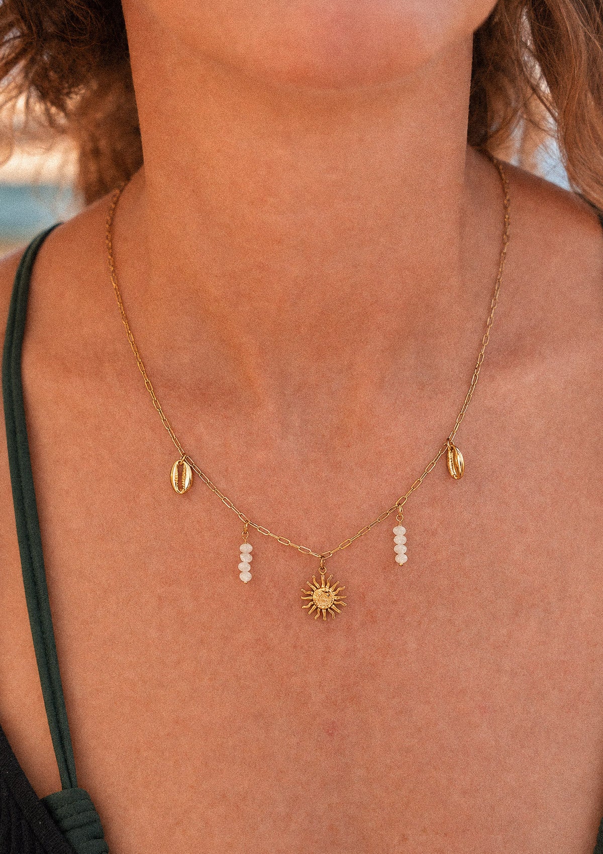 Collier Rivage d'Été porté au cou avec pendentif soleil doré, coquillages cauri et perles de Nacre, bijou solaire assemblé en France par Namaka