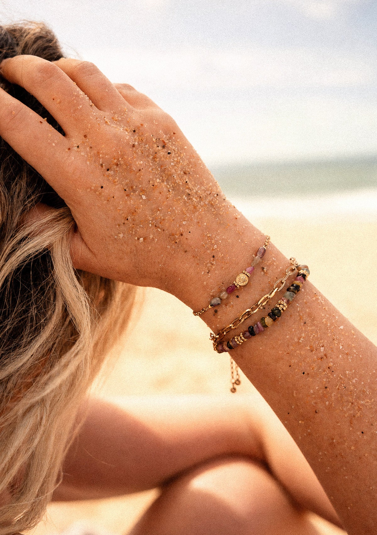 Bracelet Alliance Protectrice en Tourmaline multicolore du Brésil porté au poignet en accumulation sur plage, bijou Namaka assemblé en France