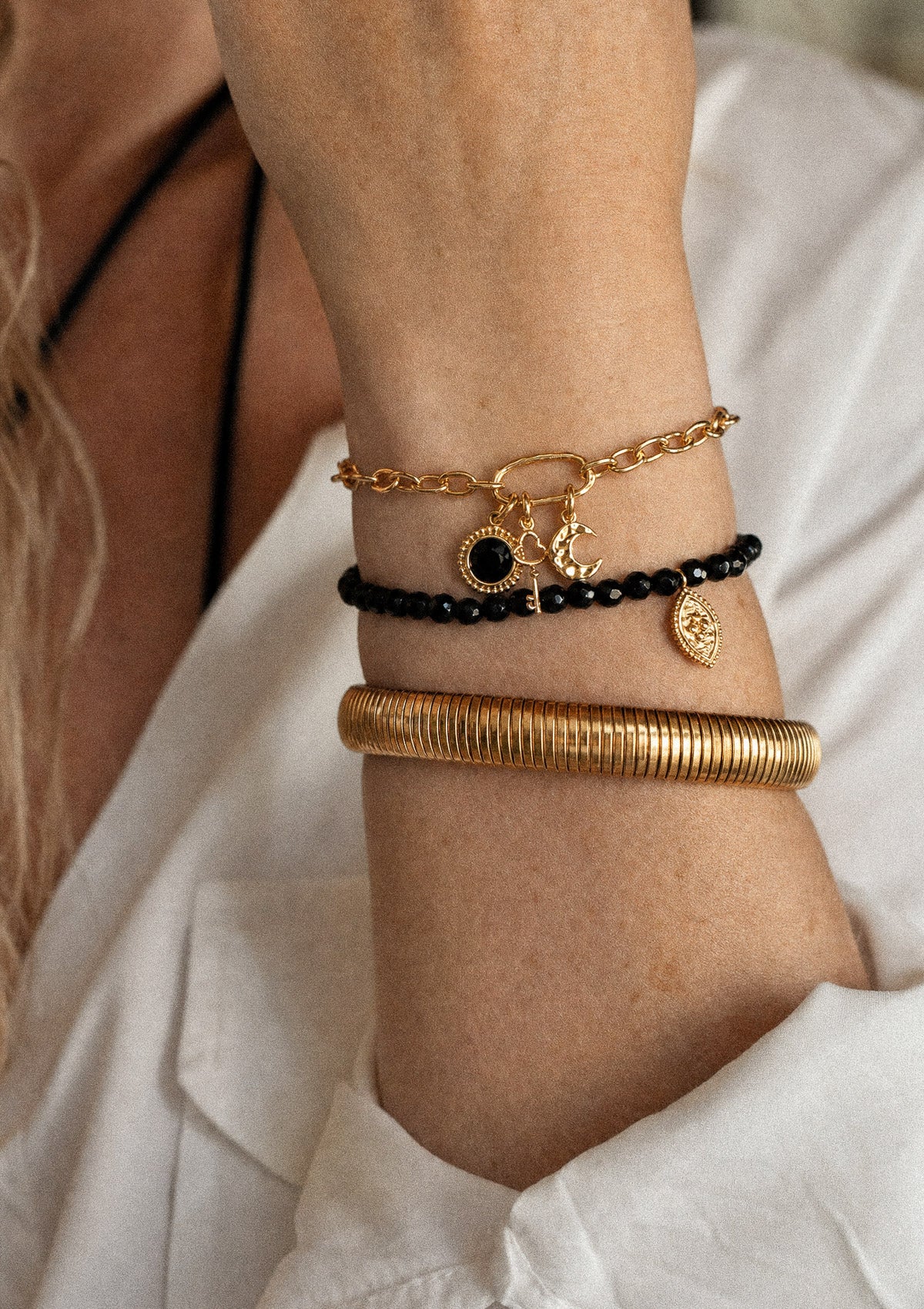 Gros plan bracelet or 18 carats à charms Onyx médaillon clé lune en accumulation avec jonc doré strié et perles Onyx facettées