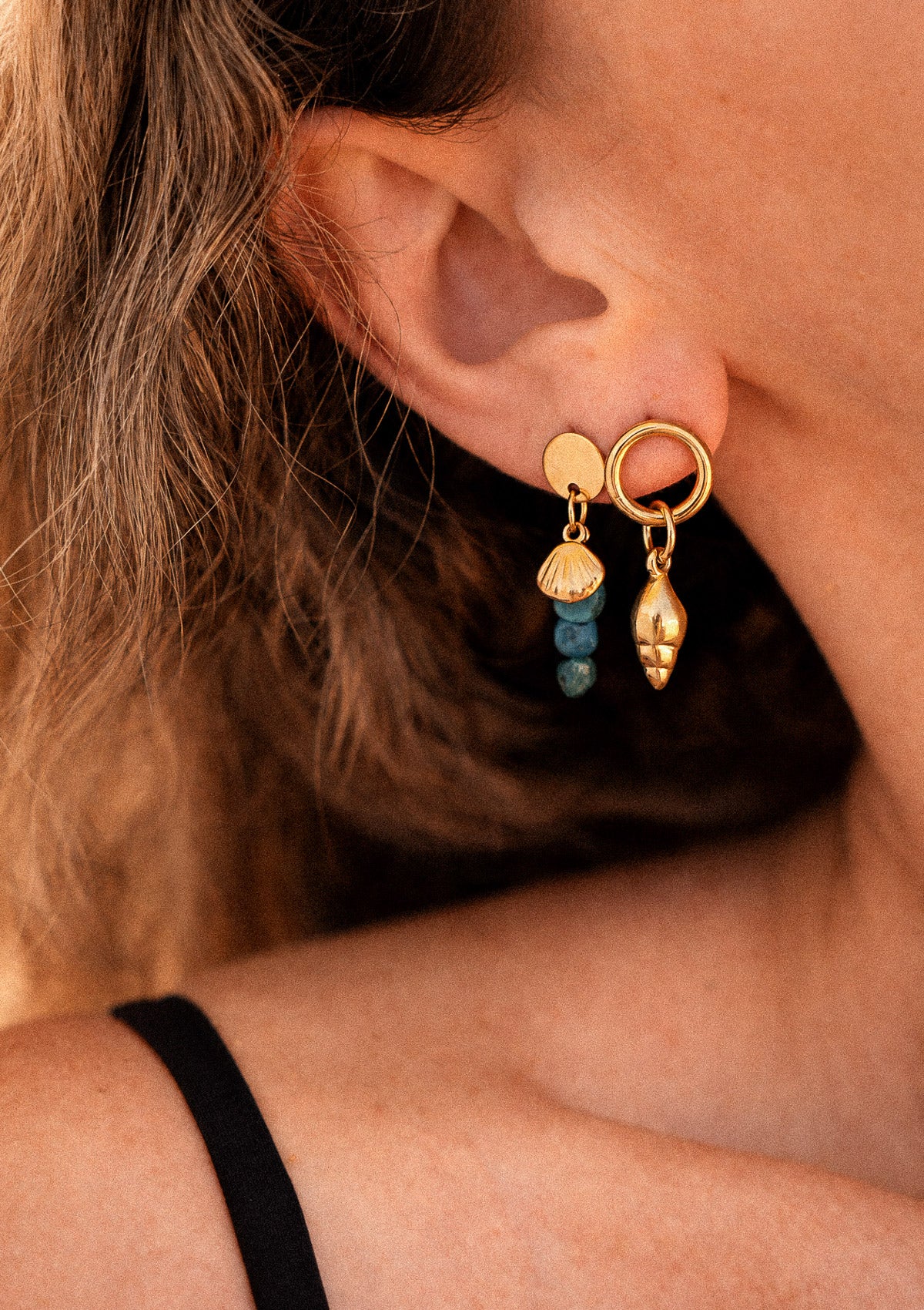 Boucles d'oreilles Azurite Coquillage Intuitif, charm coquillage doré et perles azurite bleues, portées à l'oreille en lumière chaude d'été – Namaka collection Solaire