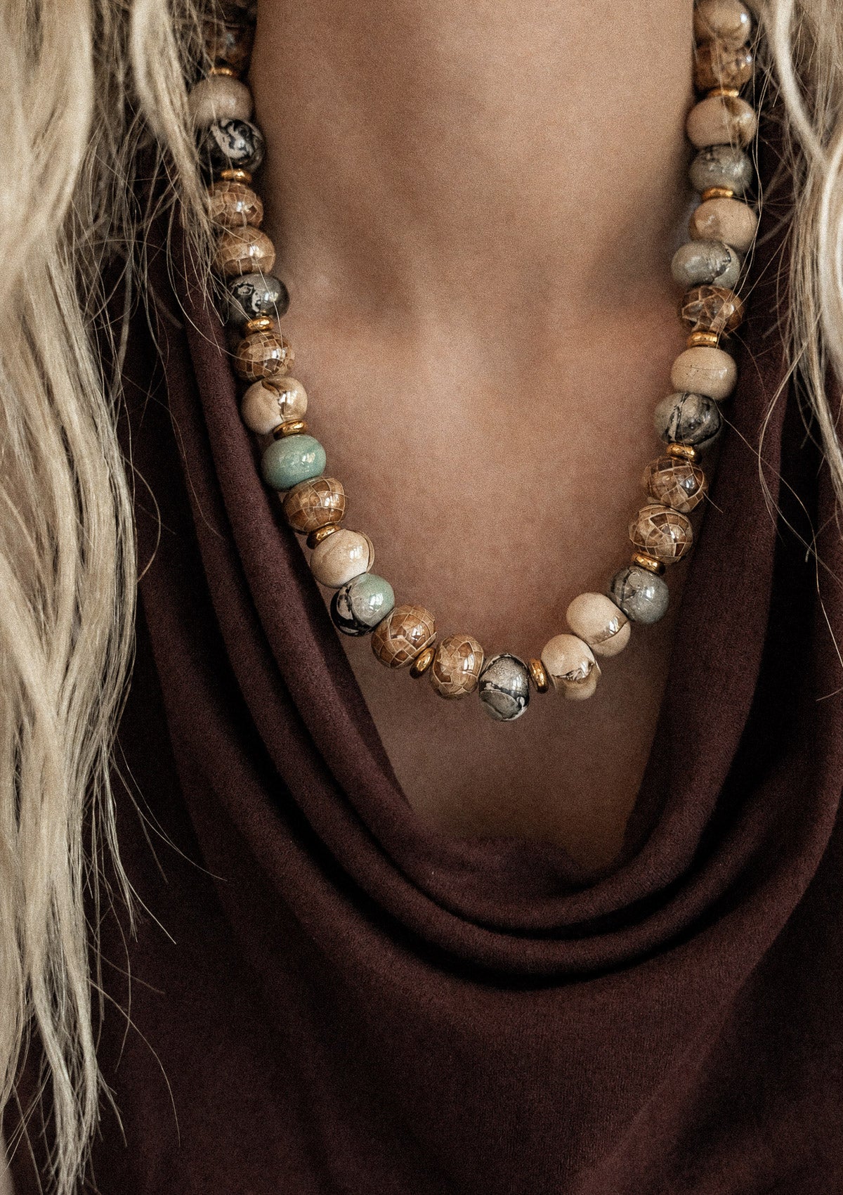 Gros plan collier ras-de-cou perles céramique émaillée teintes automnales sur top drapé velours marron chocolat, assemblé en France