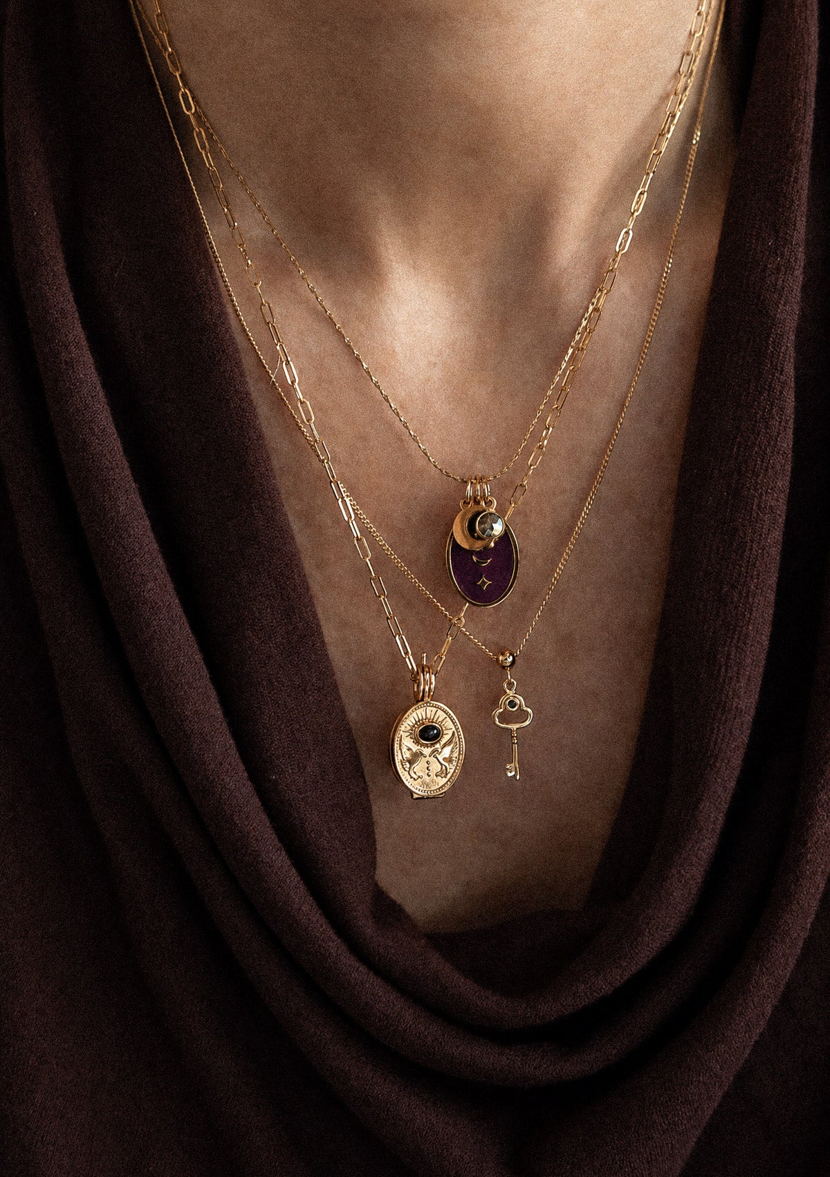 Superposition trois colliers or recyclé 18 carats sur drapé velours marron : Chemin se Révèle Onyx paperclip, Oracle Lunaire Pyrite, mini clé Onyx