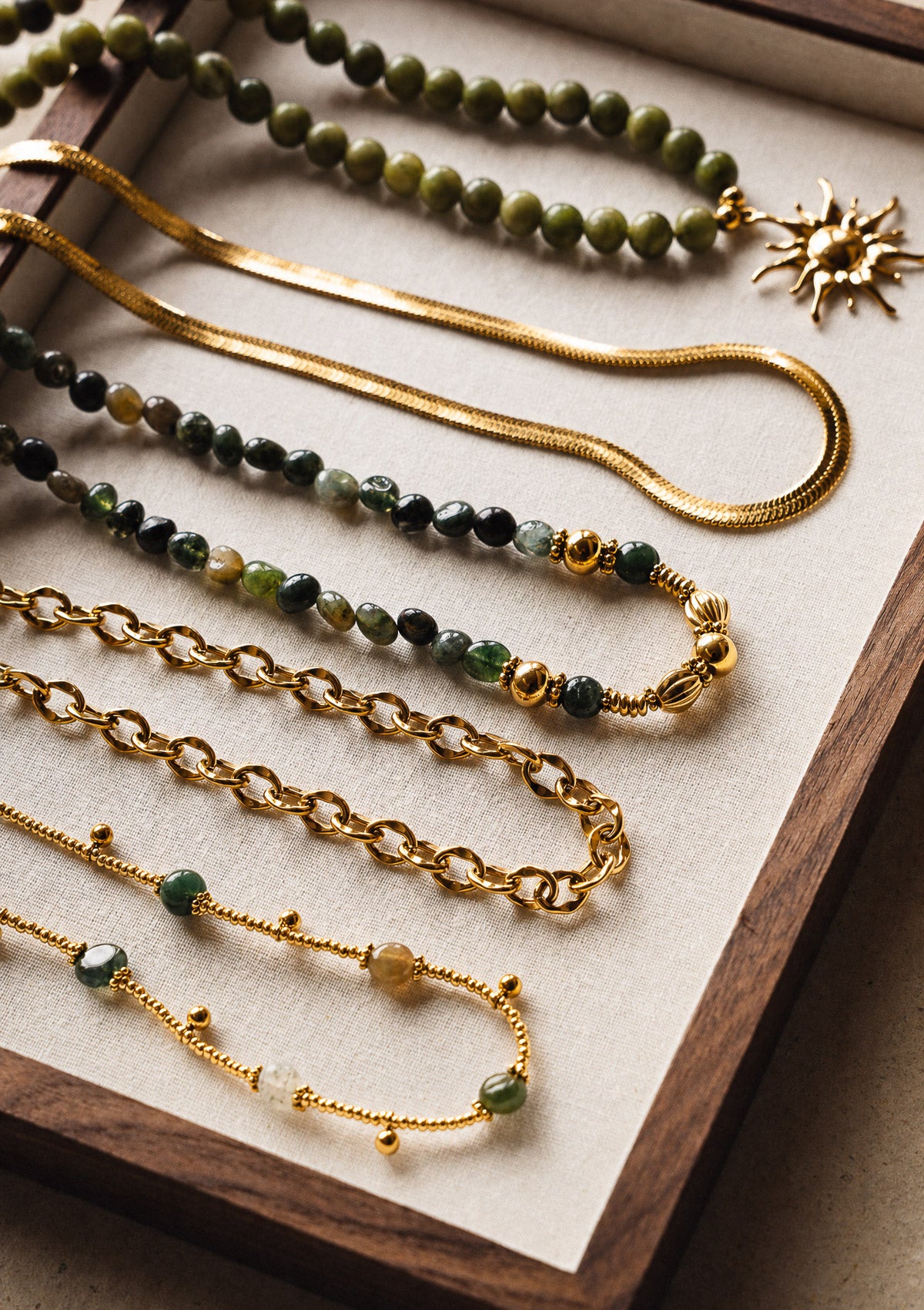 Collier chaîne serpent dorée présenté avec un ensemble de colliers Namaka, ambiance bohème et naturelle