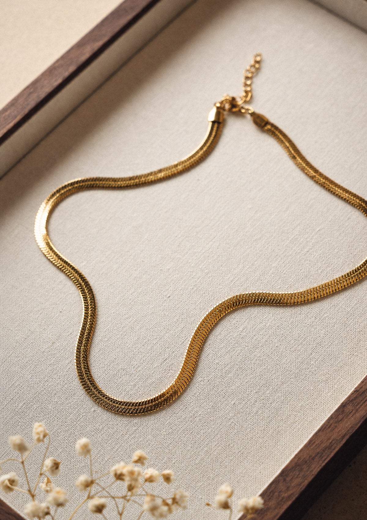 Détail du collier chaîne serpent plate en acier inoxydable doré au tombé fluide, bijou minimaliste signé Namaka