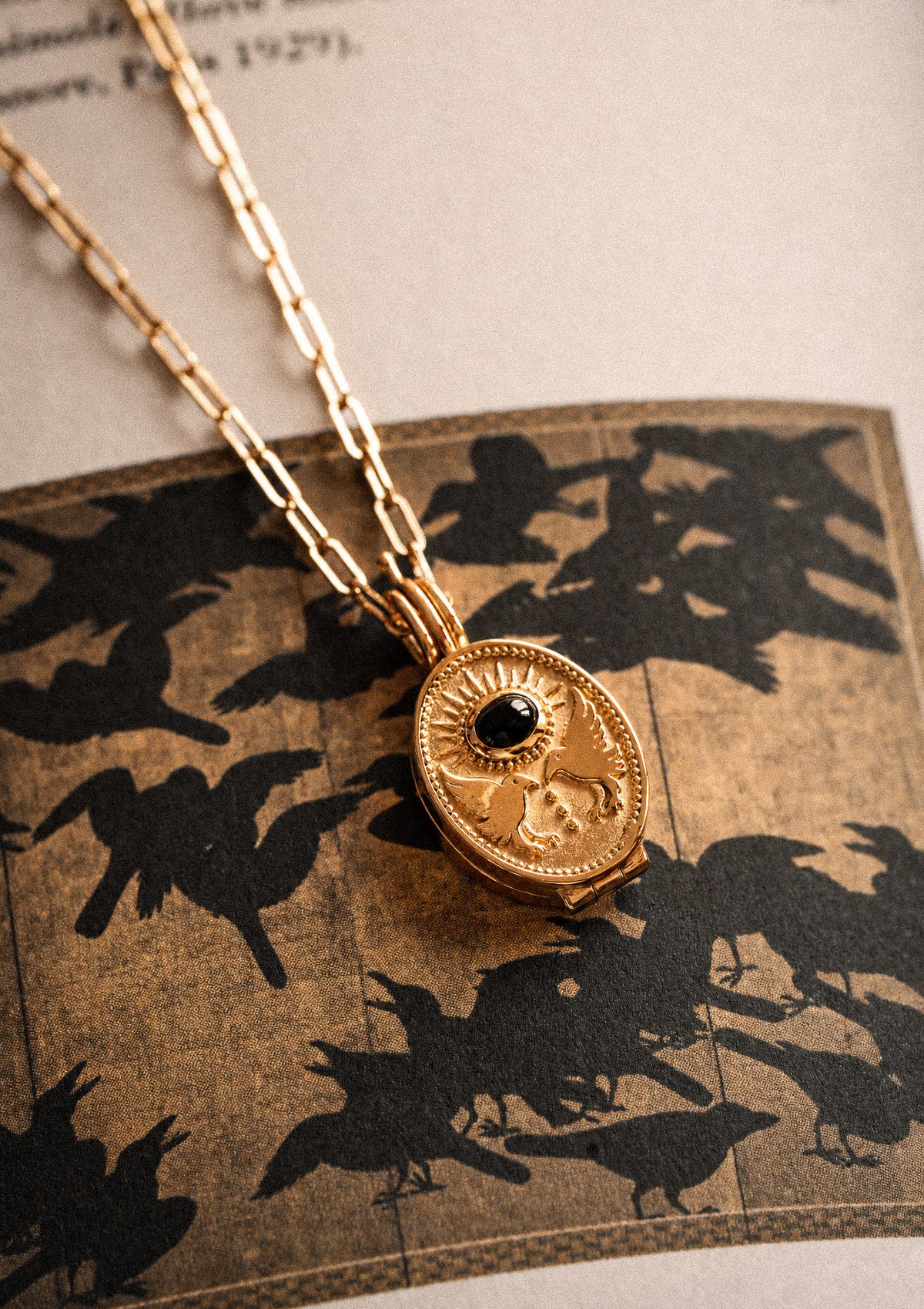 Packshot pendentif médaillon oval or 18 carats rayons dorés cabochon Onyx Noir et deux oiseaux gravés, chaîne paperclip