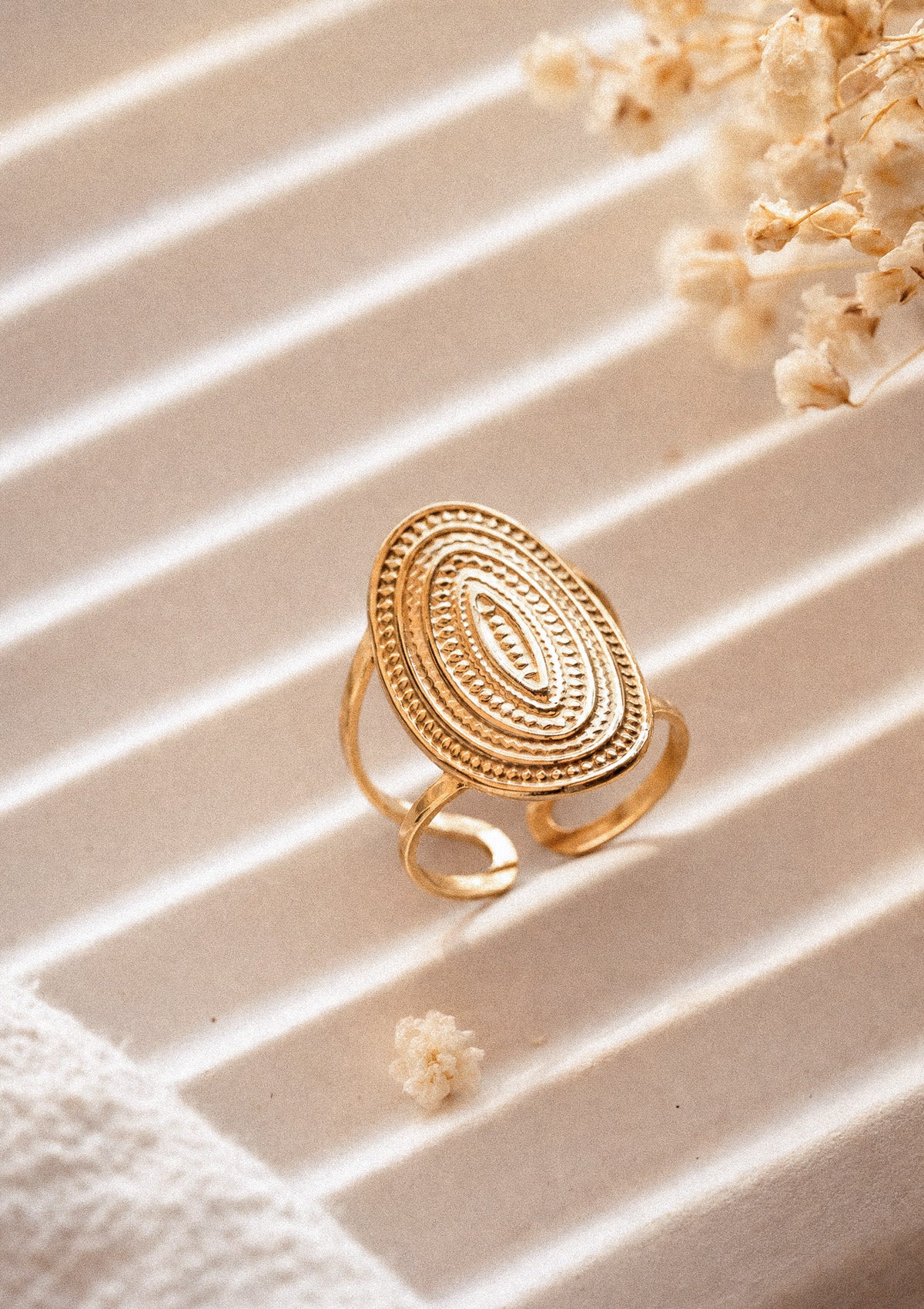 Bague Ovale Astre Intérieur packshot, plateau ovale doré aux cercles concentriques perlés signature ethnique, ombres lumineuses – acier inoxydable doré Namaka collection Solaire