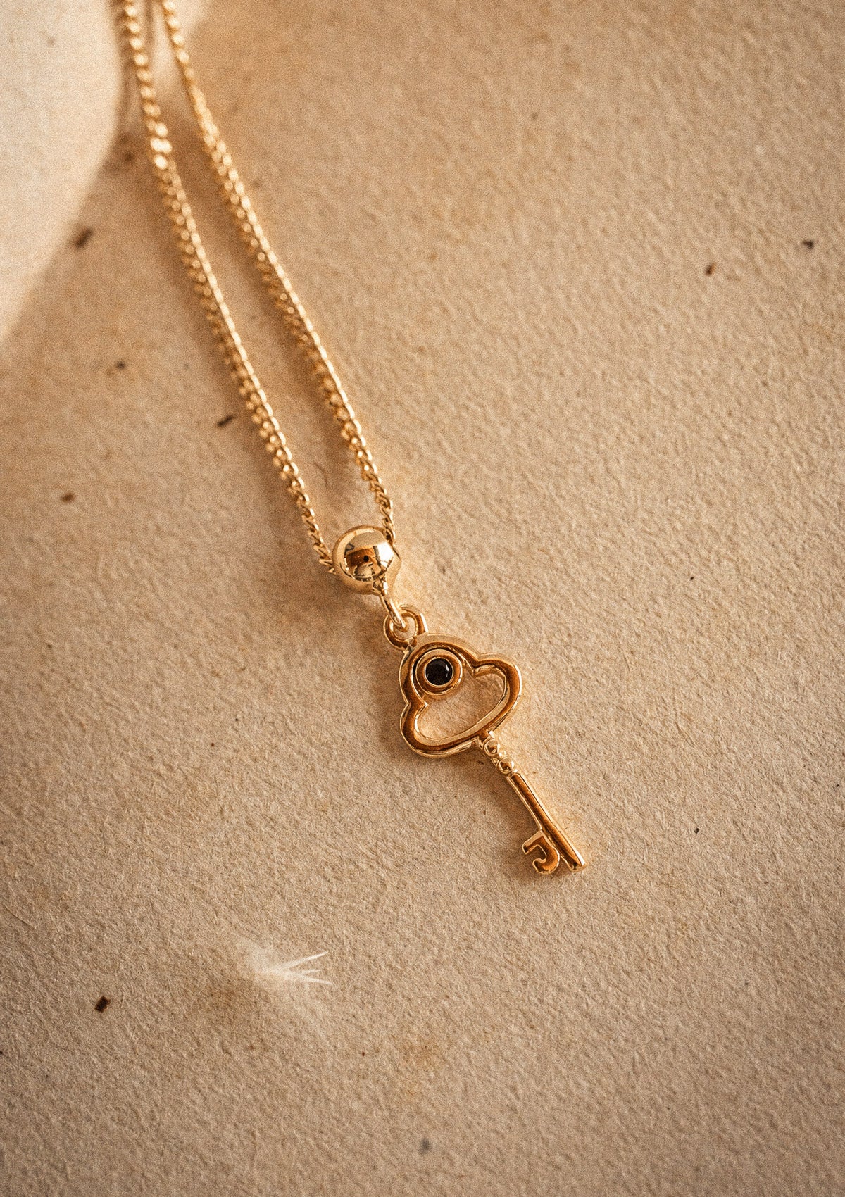 Packshot pendentif mini clé or recyclé 18 carats anneau cœur cabochon Onyx Noir sur chaîne fine dorée à billes
