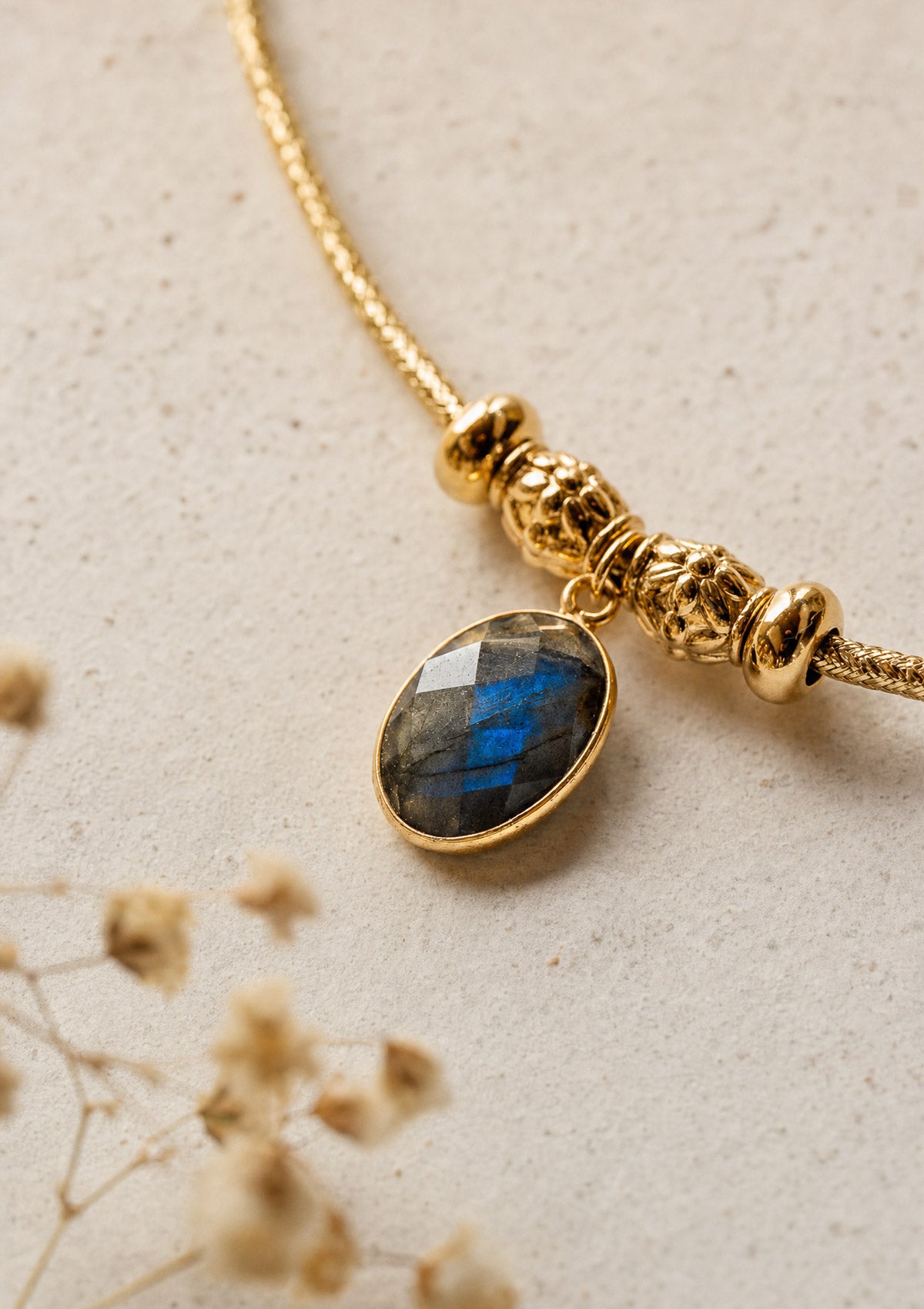 Gros plan sur la Labradorite naturelle facettée aux reflets bleus, pendentif serti d'or sur torque rigide assemblé en France par Namaka