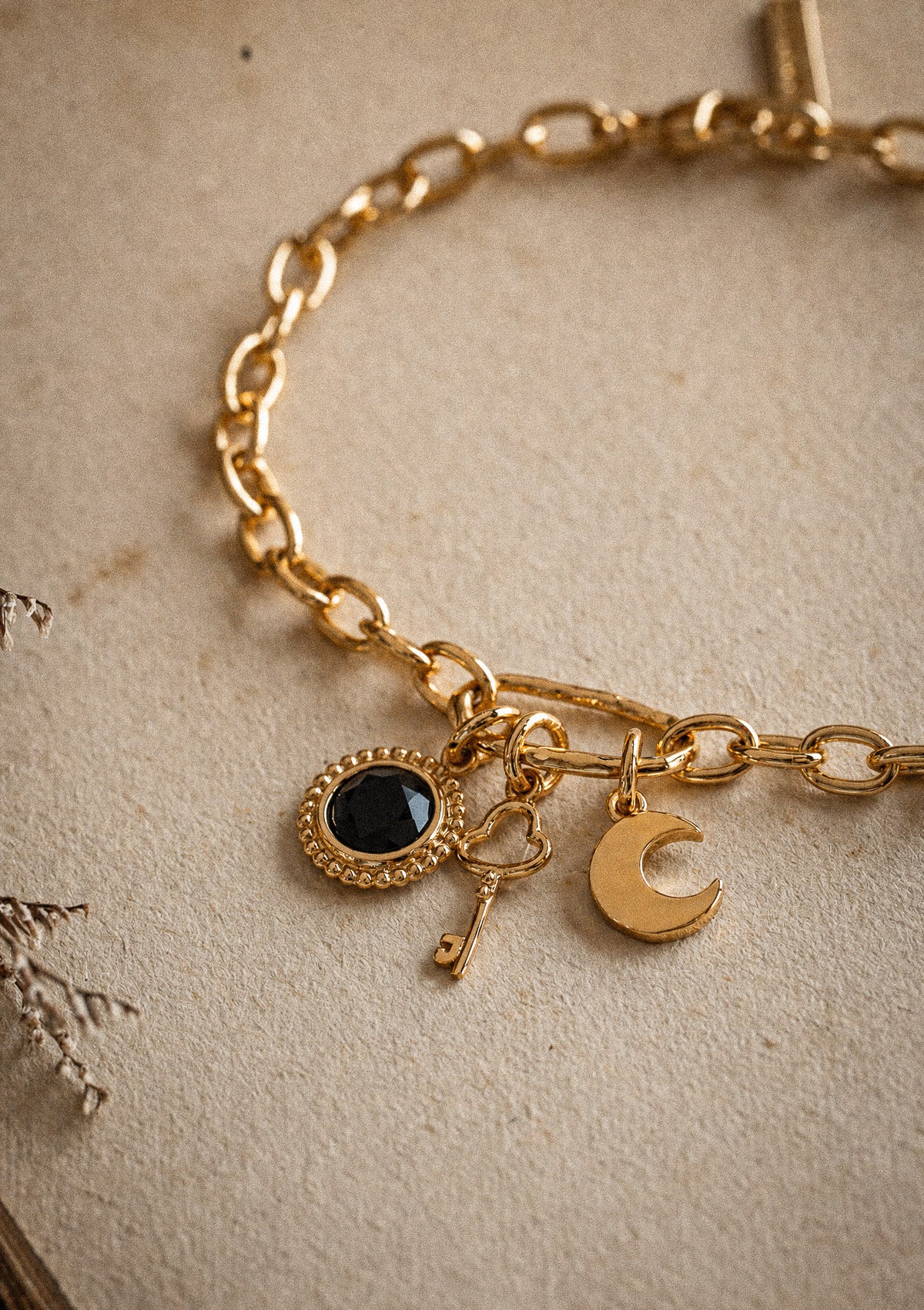 Packshot bracelet or recyclé 18 carats maille ovale avec trois charms : médaillon Onyx Noir contour perlé, clé cœur, lune croissant