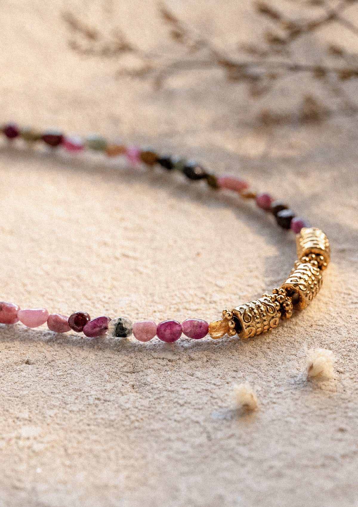 Gros plan barrettes dorées ornées et perles de Tourmaline multicolore nuggets du collier Harmonie Vivante sur sable – Namaka collection Solaire, assemblé en France