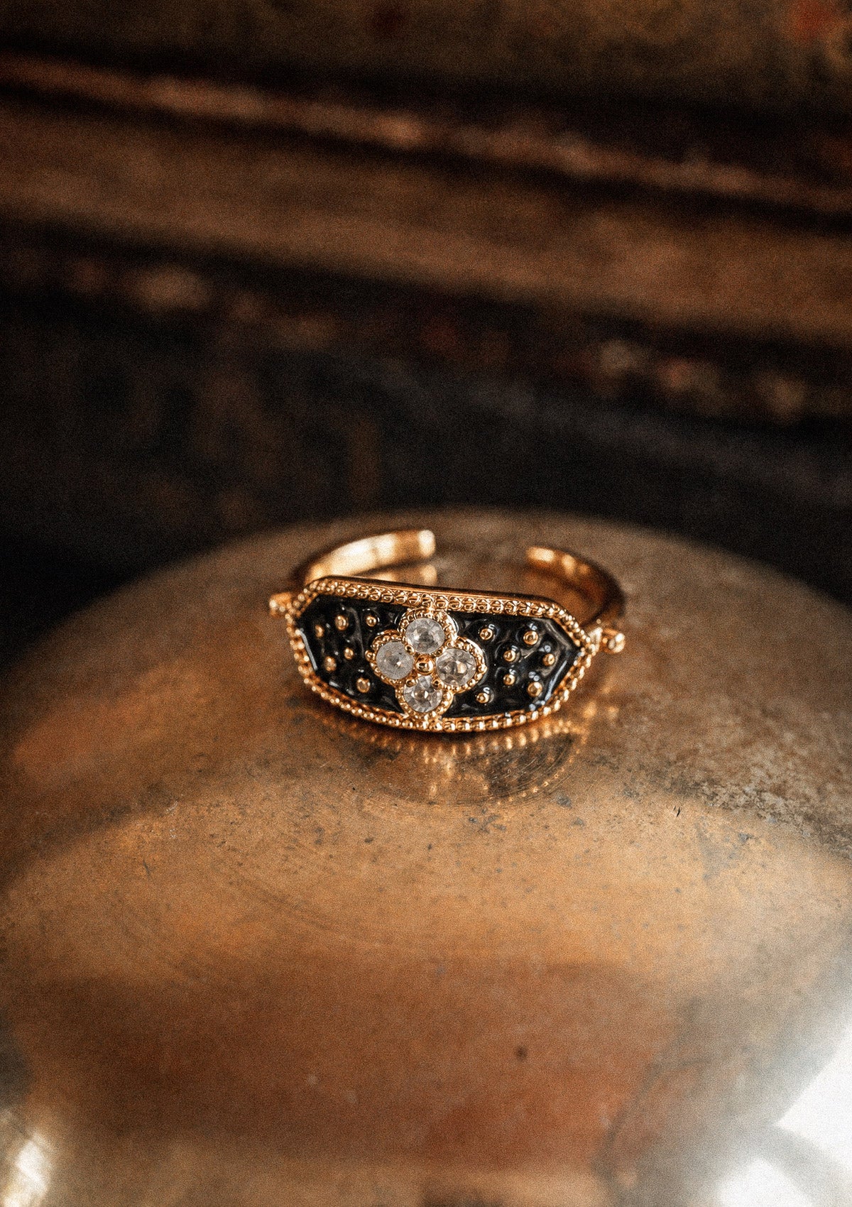 Packshot bague or 18 carats plateau émail noir constellé quatre Pierres de Lune motif trèfle sur coupelle laiton dorée