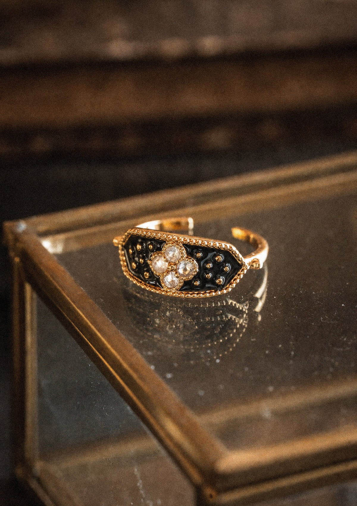 Packshot bague or recyclé 18 carats plateau émail noir constellé perles dorées serti quatre Pierres de Lune motif trèfle, pierre d'intuition