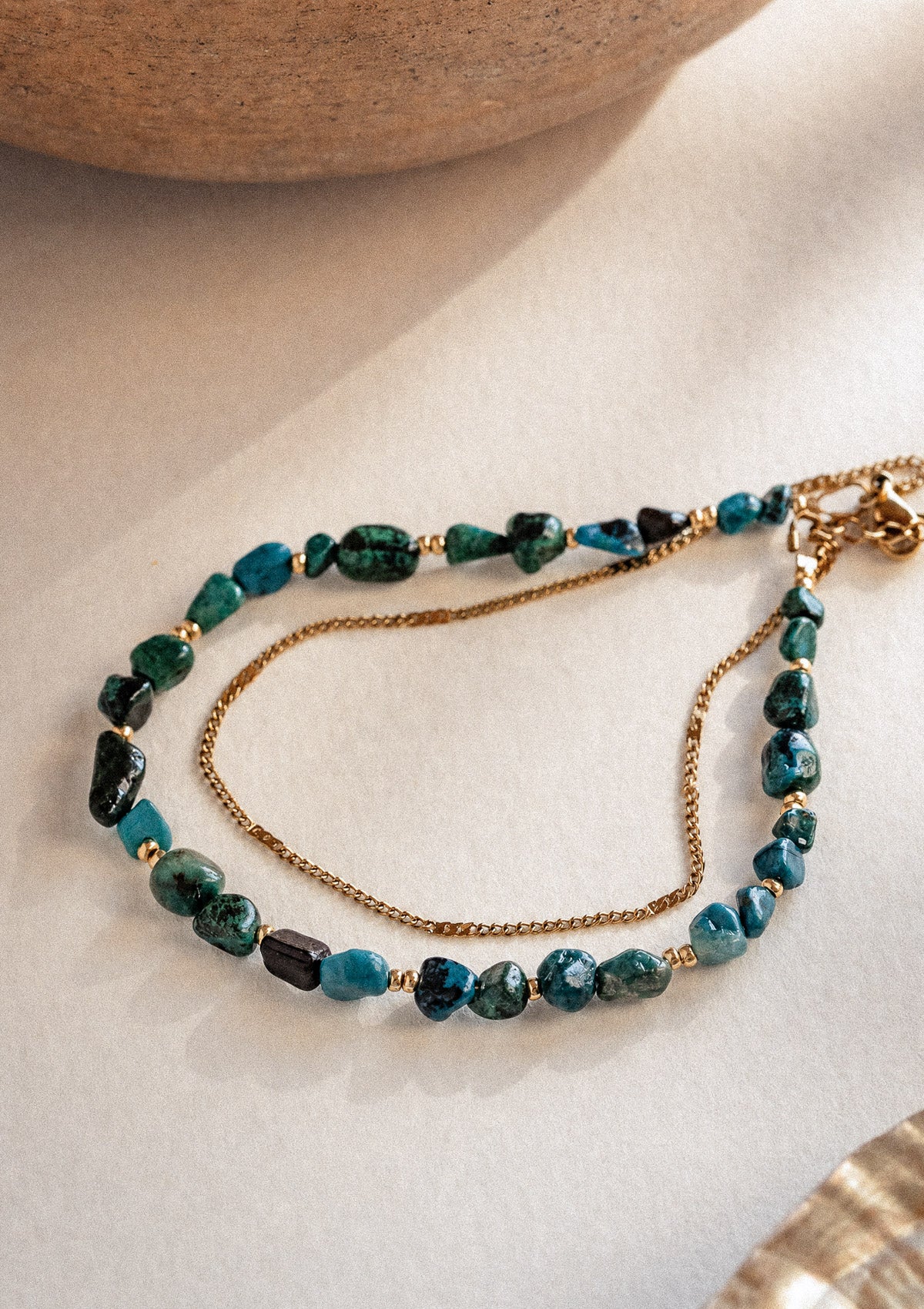 Bracelet Double Azurite Juste ressenti packshot, double rang perles brutes bleu profond et chaîne fine dorée, sous bol en bois – Namaka collection Solaire, assemblé en France
