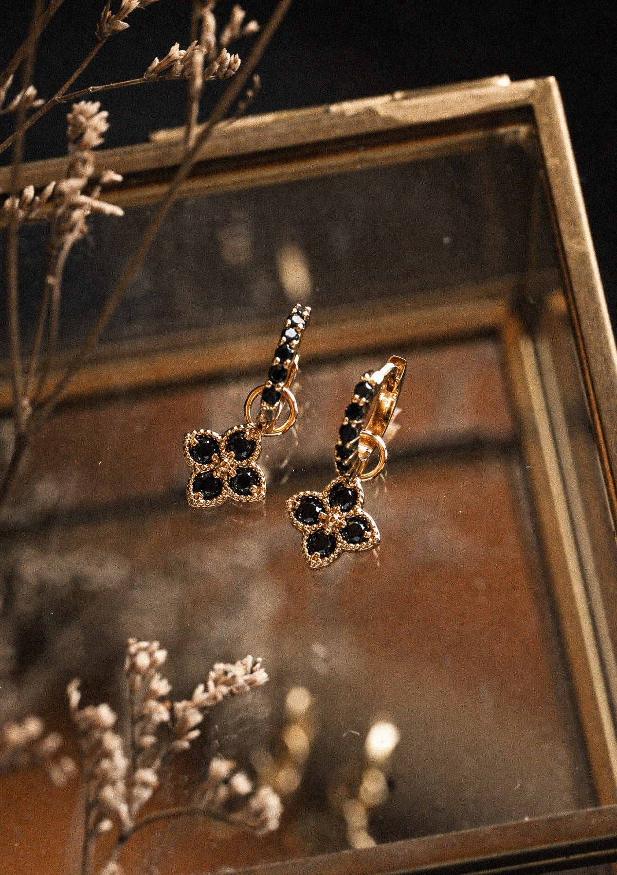 Packshot deux mini créoles or recyclé 18 carats serties Onyx Noir avec charm rosace quatre pétales cabochons Onyx, pierre de protection