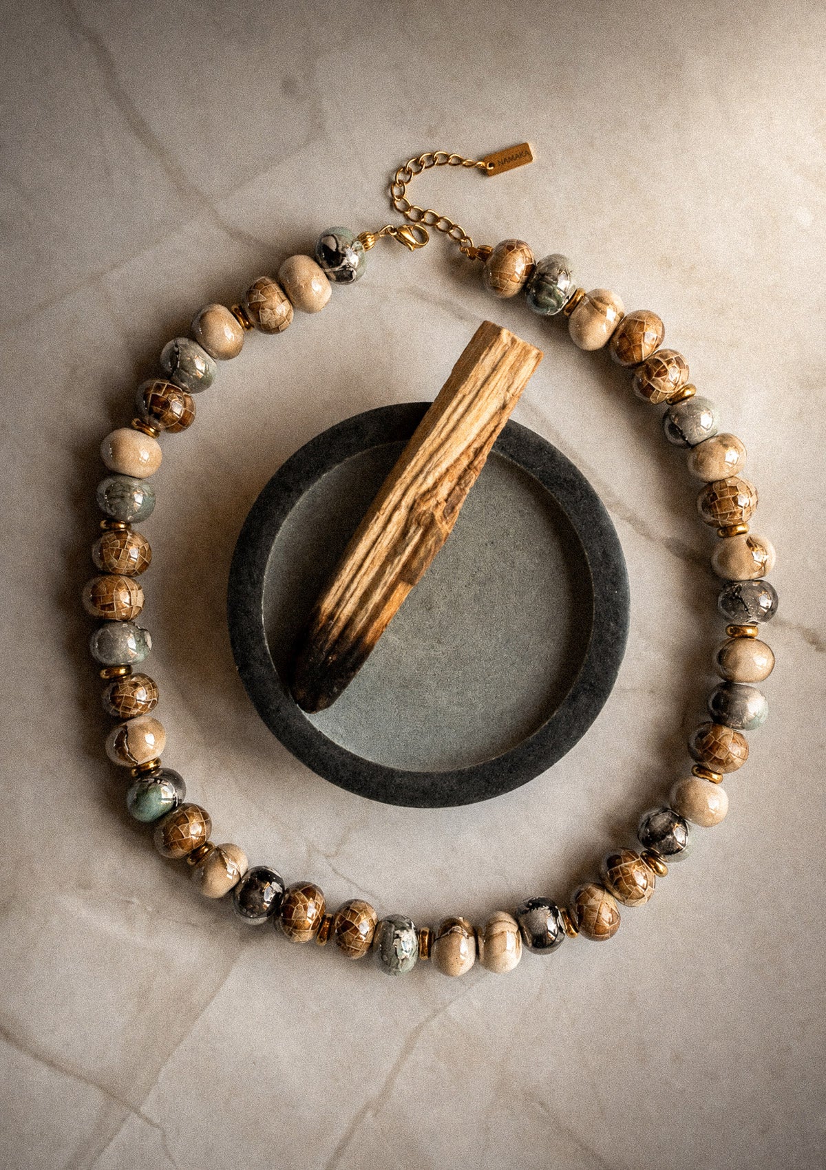 Packshot collier ras-de-cou grosses perles céramique émaillée teintes brun ivoire gris marbré et vert amande, assemblé en France