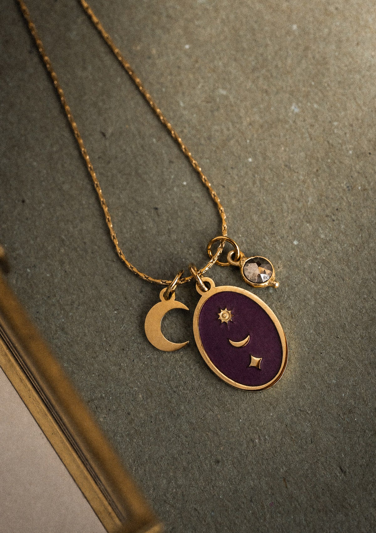 Packshot collier chaîne fine acier doré médaillon oval émail bordeaux motifs lune soleil étoile, charm croissant et cabochon Pyrite