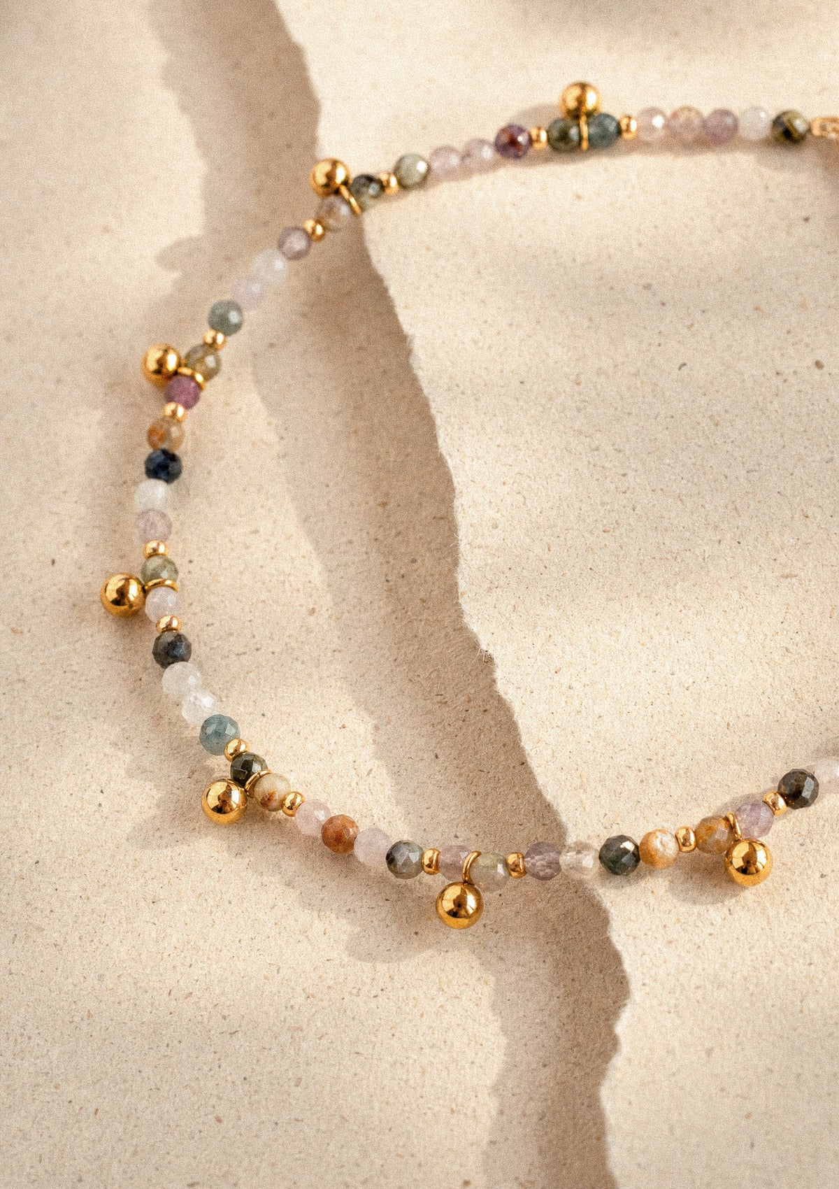 Gros plan cheville Élan Doré, détail des perles Tourmaline multicolore facettées et pampilles perles dorées sur chaîne fine – Namaka collection Solaire, assemblé en France