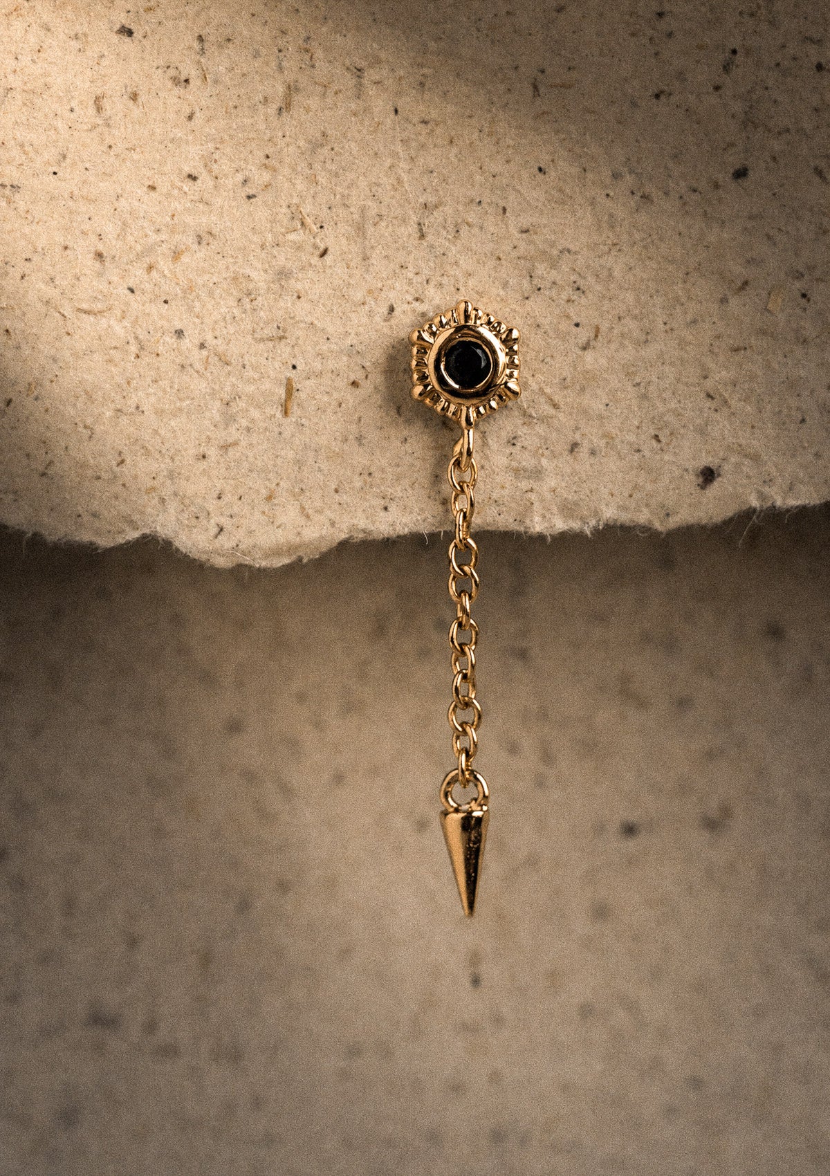 Packshot mini puce or recyclé 18 carats fleur soleil rayonnante sertie cabochon Onyx Noir central, chaîne fine et pointe pique dorée
