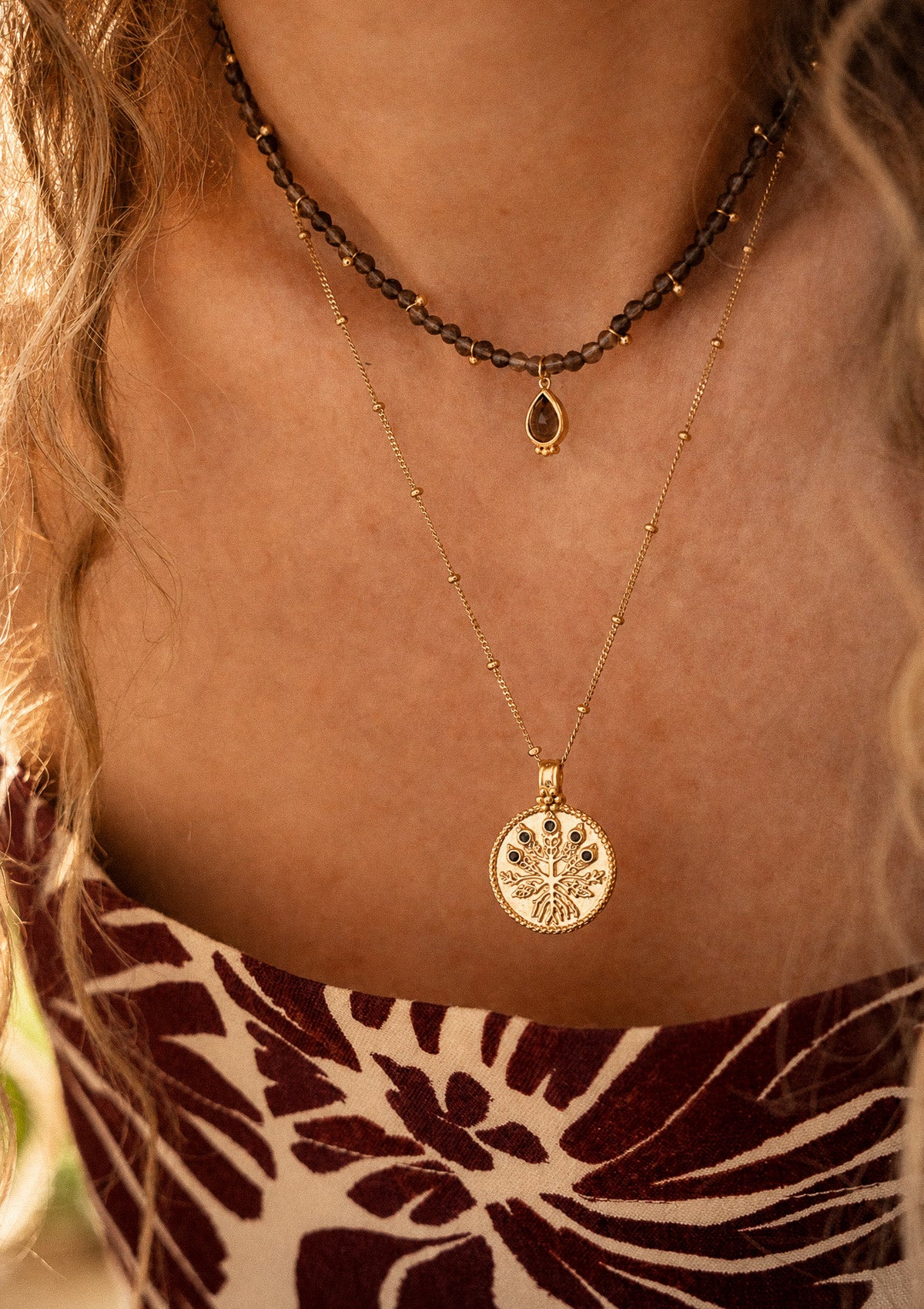 Collier médaillon Racines Sauvages porté en accumulation avec un ras-du-cou Quartz Fumé Instinct Profond, bijoux symboliques en or recyclé Namaka