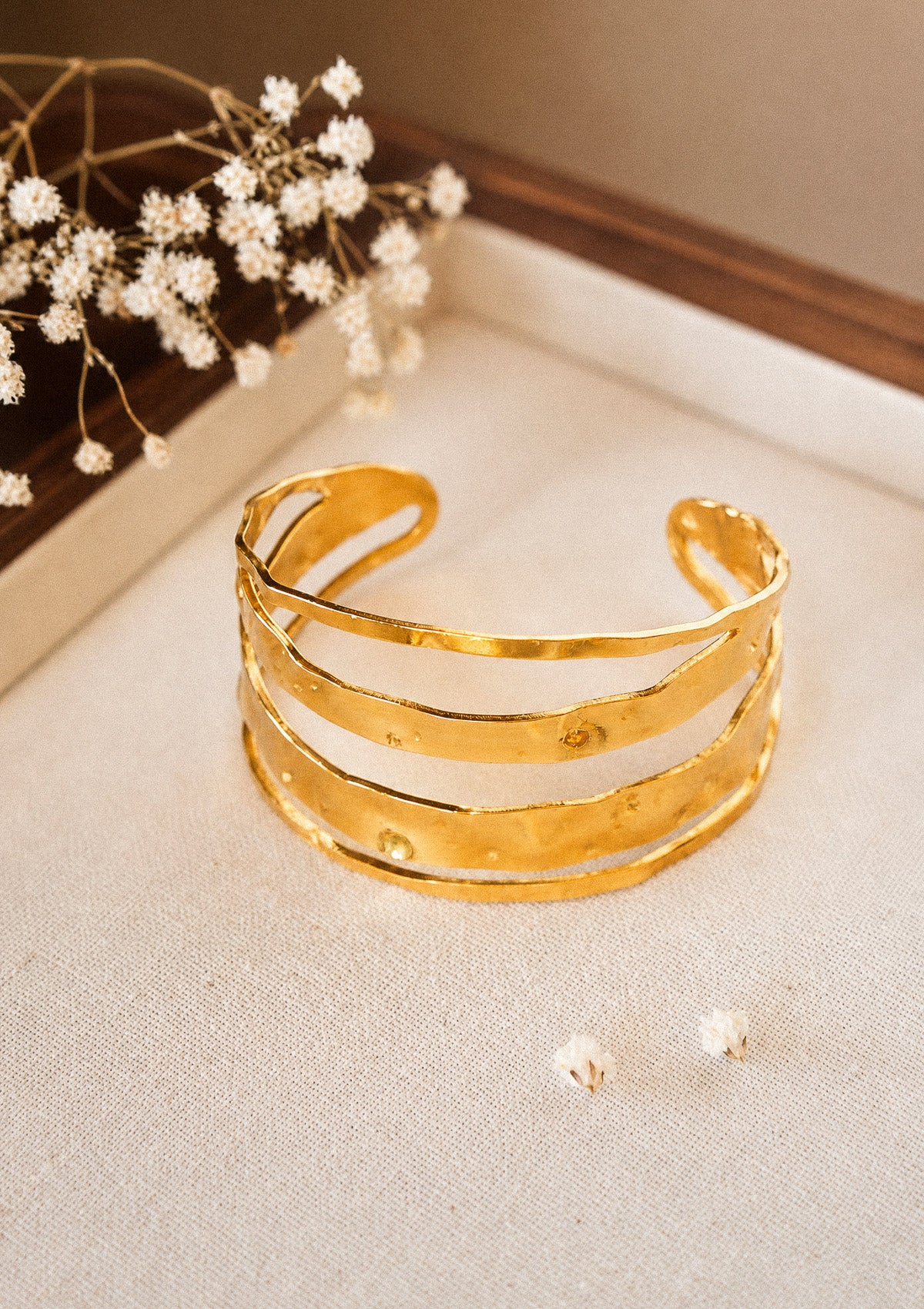 Bracelet jonc en acier inoxydable doré à quatre lignes ondulantes martelées ajourées 60 x 31 mm à ouverture ajustable signé Namaka