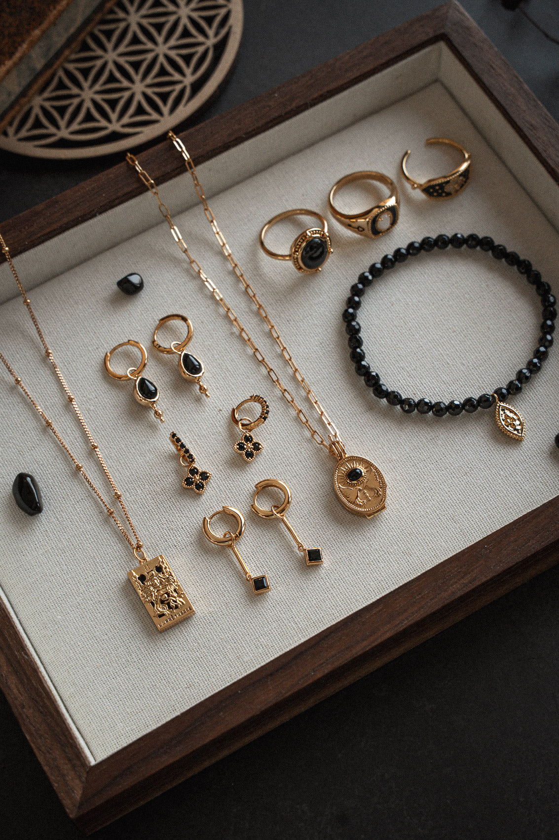 Bijoux or recyclé 18 carats et Onyx Noir sur plateau bois : collier tarot La Prêtresse, médaillon Chemin, boucles pampilles, chevalière, bracelet perles