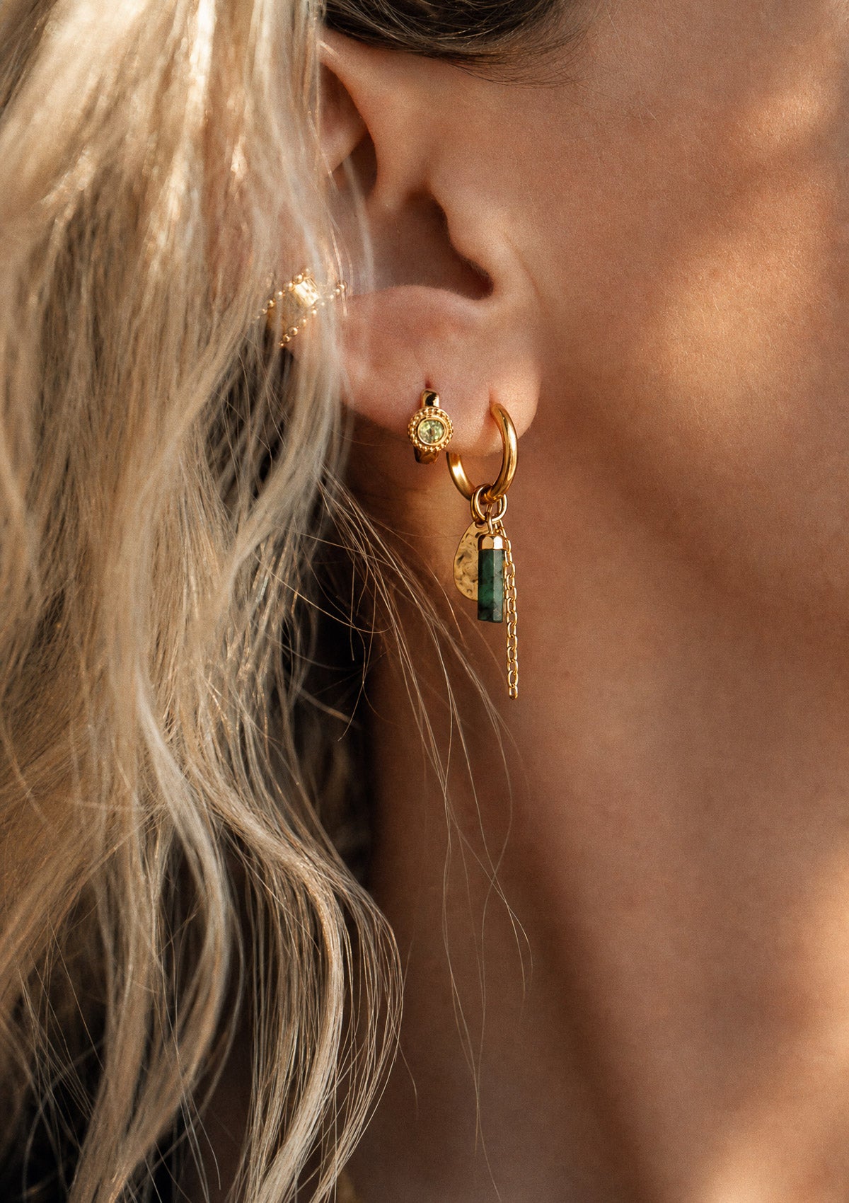 Mini créole Péridot dorée portée à l'oreille en accumulation avec une créole pampille Émeraude et un ear cuff, inspiration bohème Namaka